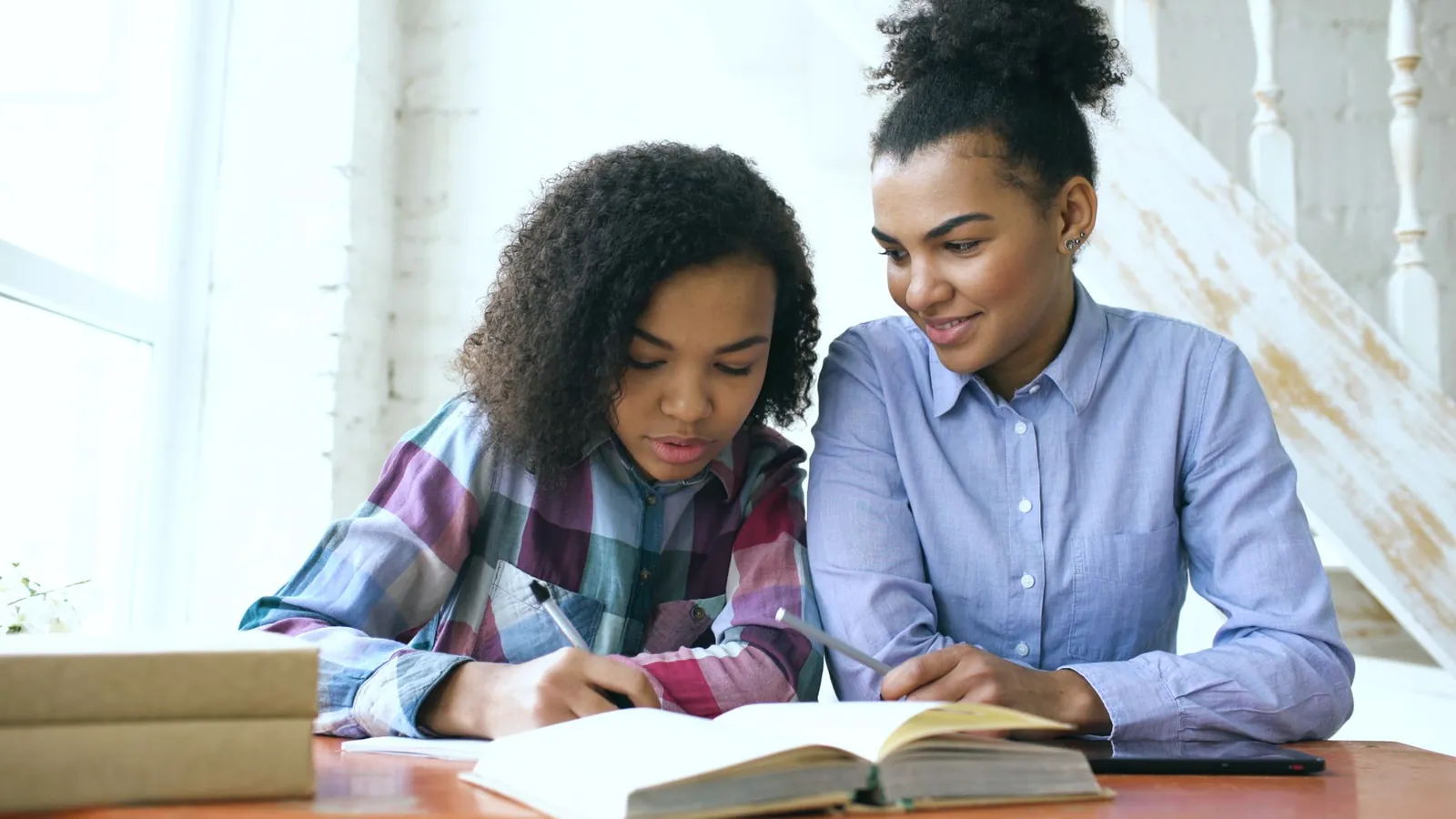 Tutrice qui aide une adolescente à faire ses devoirs à une table d'étude