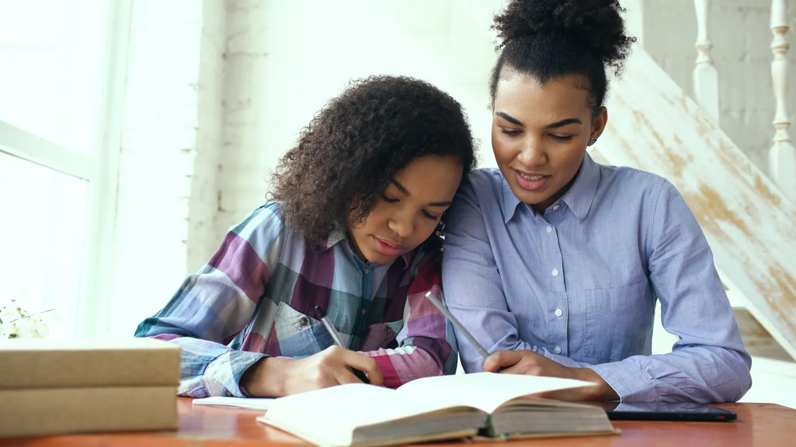 Tutrice et élève qui étudient ensemble à une table, livres ouverts